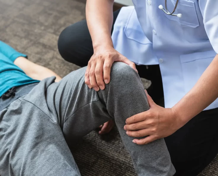 Professional orthopedic surgeon is examining a patient knee at the clinic.