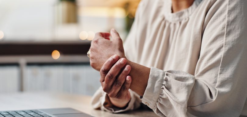 Arthritis, hands and laptop with business person at desk in office for administration or typing rep