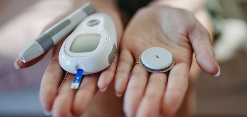 Close up of hands with diabetes supplies and devices.
