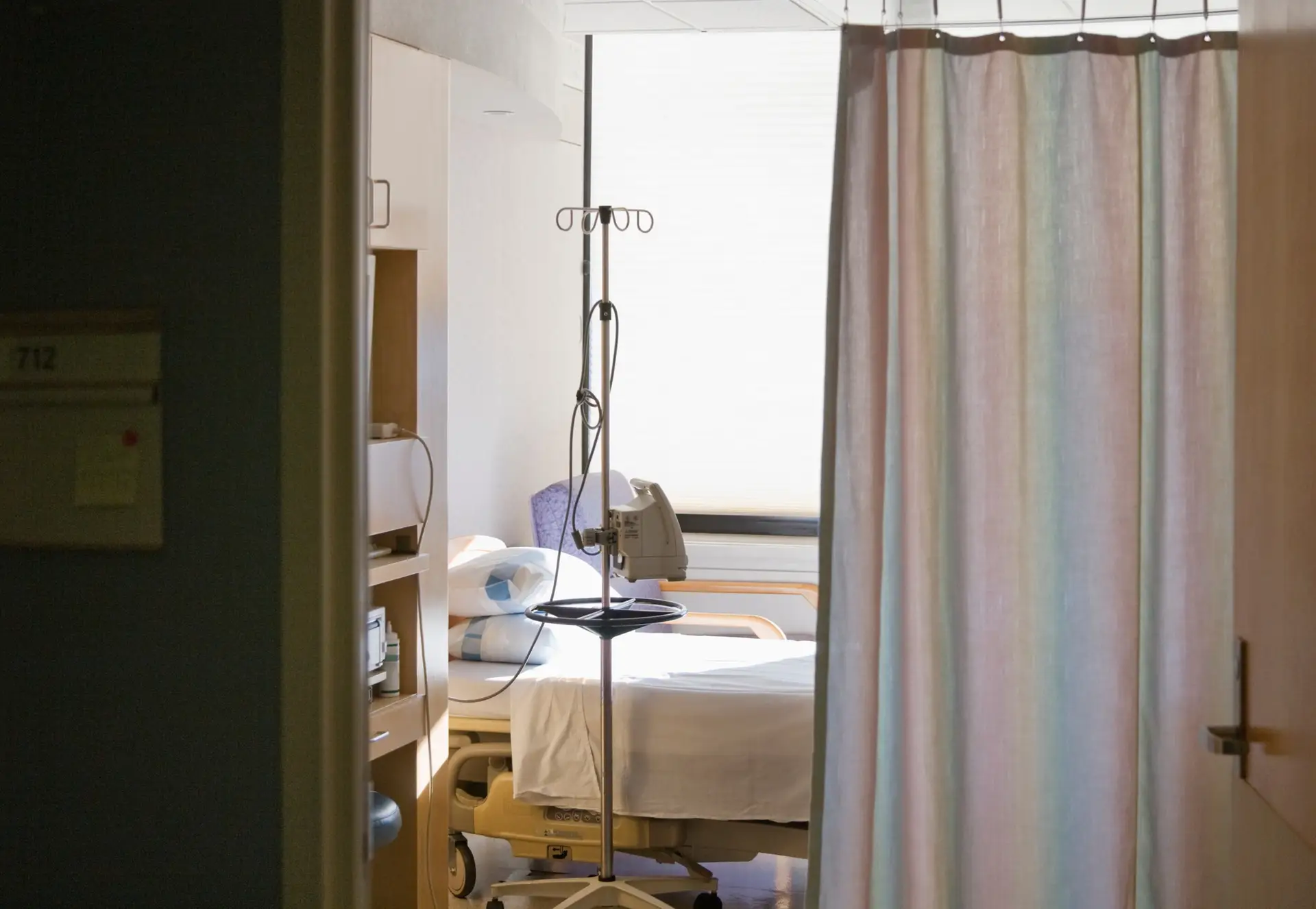 Hospital room with bed and privacy curtain.