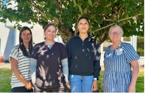 Kelly Thompson, CNO; Taz Wachendorf, MAC, Clallam Bay Medical Clinic; Sylvia Torres, NAC, Extended Care Unit and Acute Care; and Deborah Dillon, Director of Patient Safety & Quality pose in front of a tree.